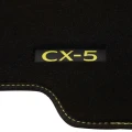 Haftowane, żółte logo na materiałowym dywaniku do Mazdy CX-5 KF Newground.
